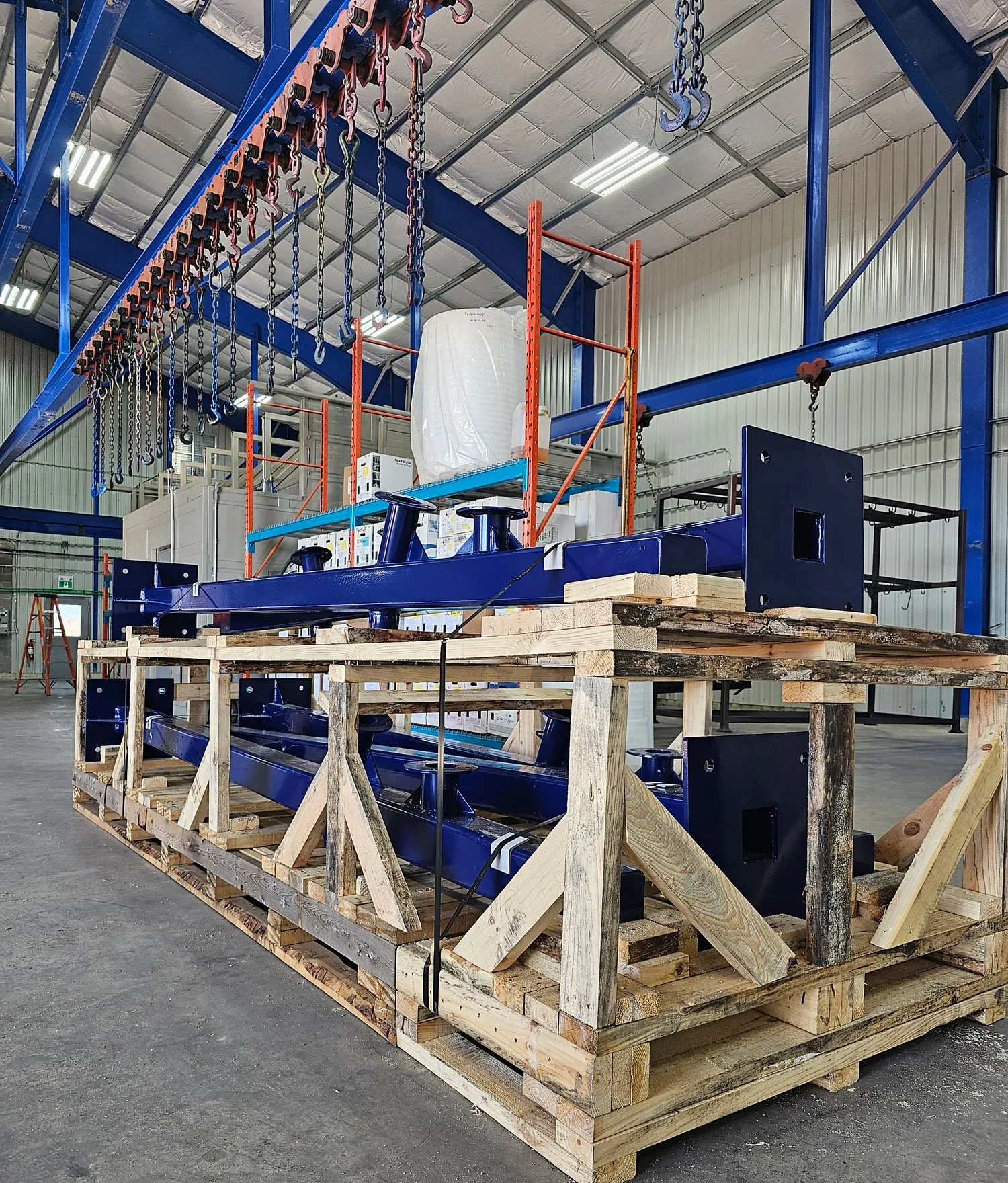 Large fabricated industrial assembly resting on wooden shipping supports inside the facility