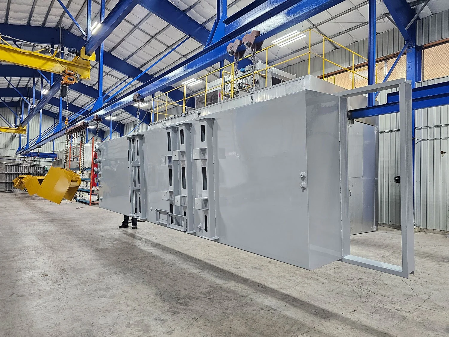 Large gray industrial enclosure suspended from the overhead production line