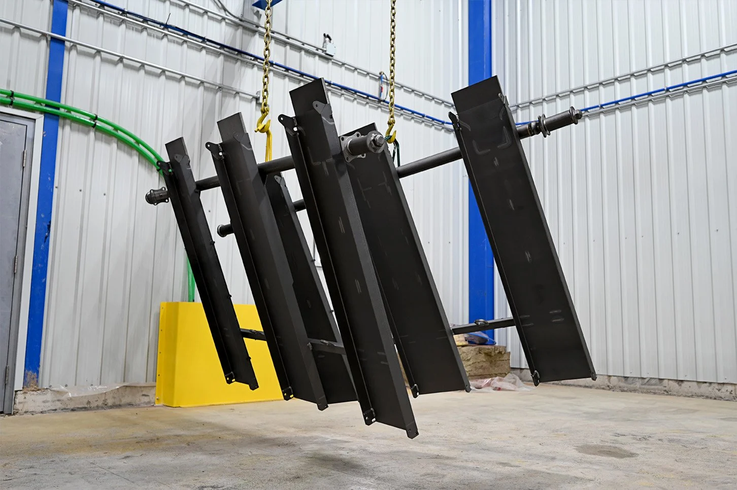 Black fabricated steel components hanging inside the coating facility