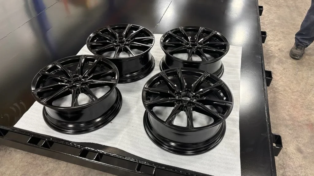 Four gloss black finished wheel rims on a cart