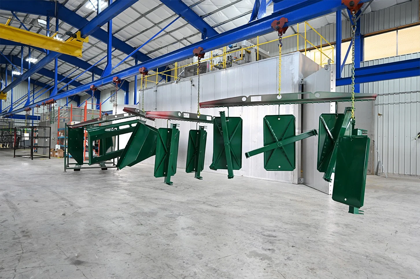 Green coated steel components hanging from the overhead production line