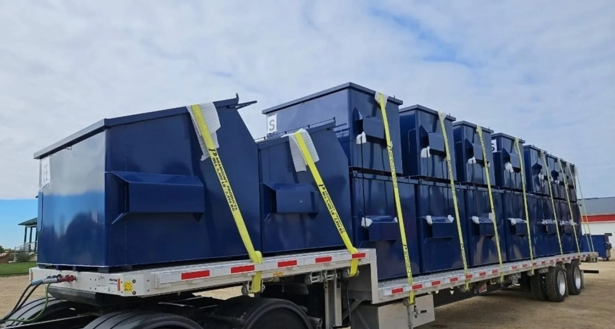 Large blue industrial enclosures loaded for transport