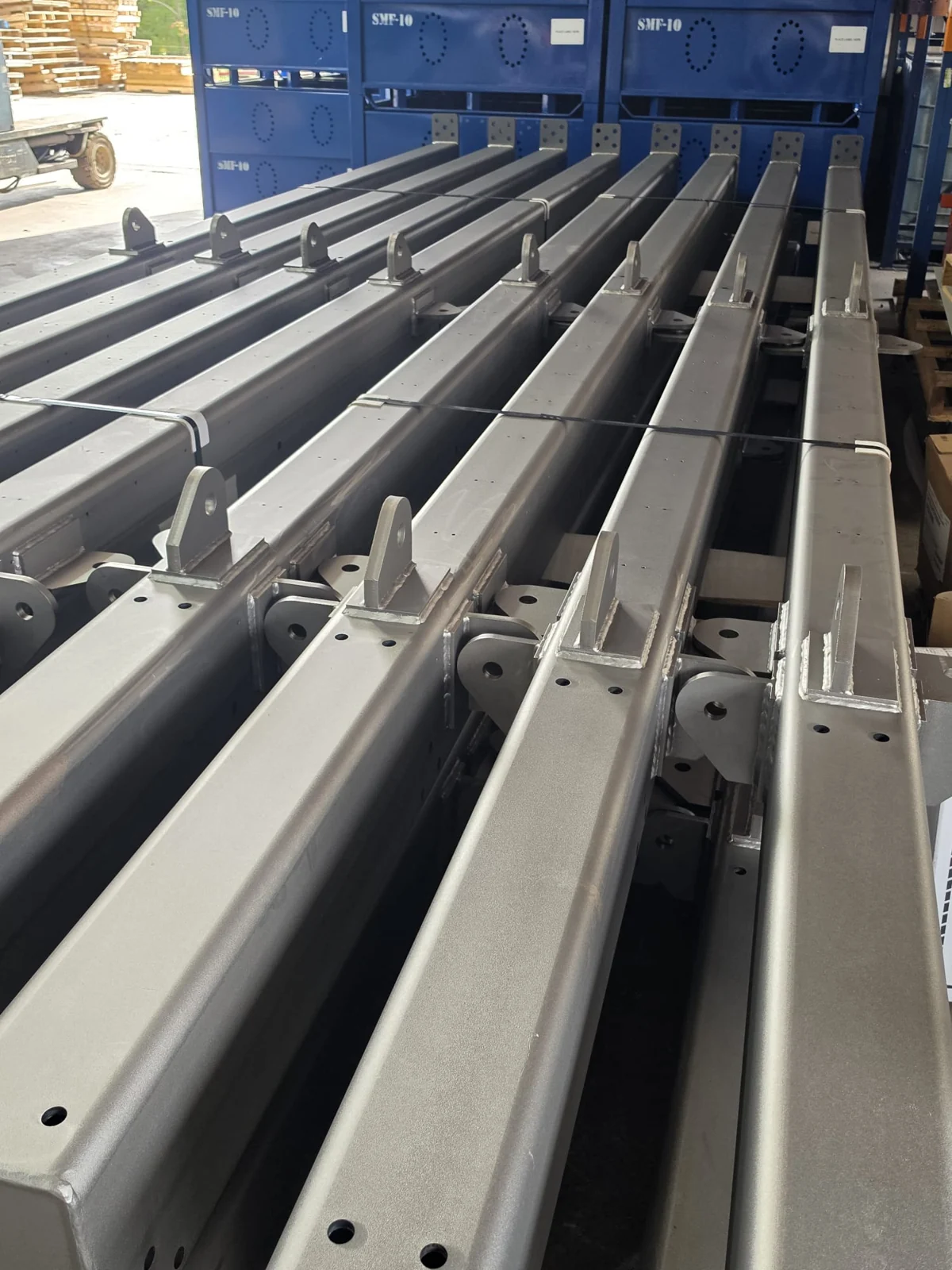 Batch of long gray steel components staged in parallel